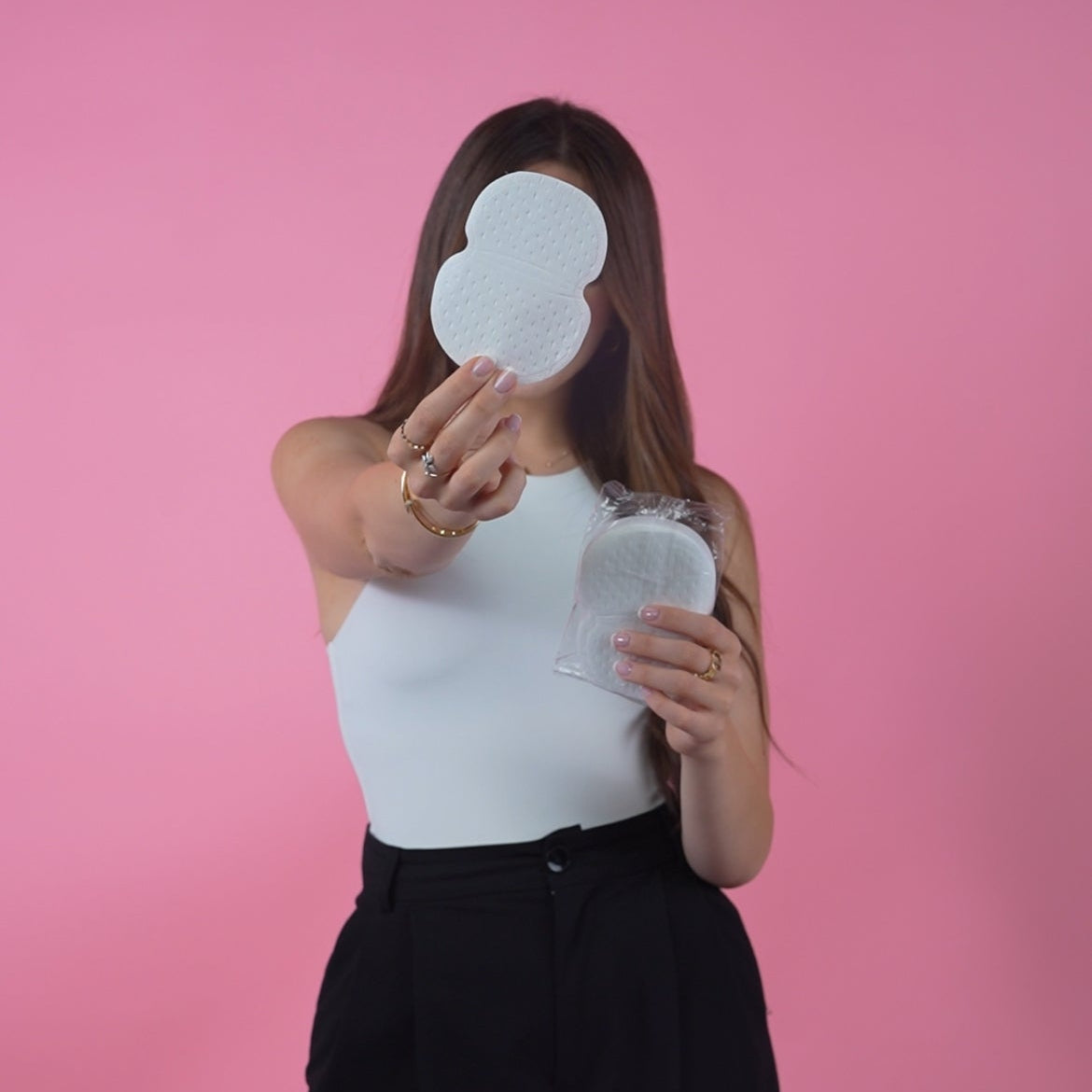 Person holding a underarm sweat pad against a pink background