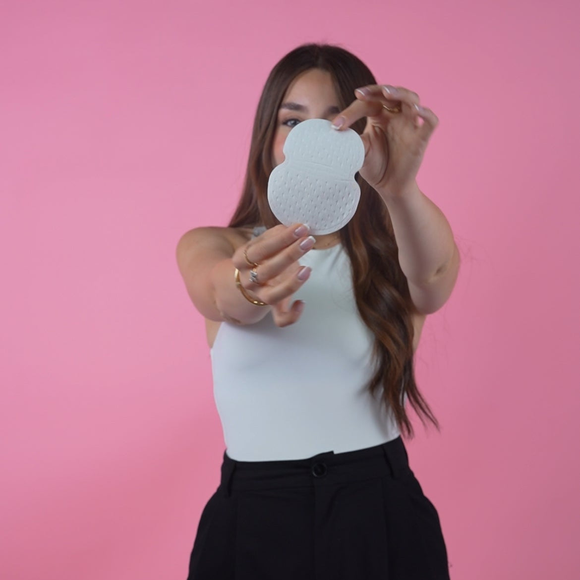 Woman holding a white round object against a pink background
